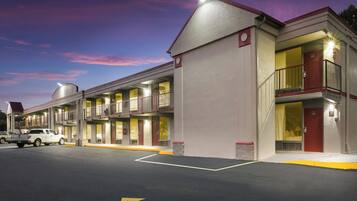 Un motel con varias habitaciones, estacionamiento y cielo despejado.