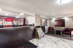 A hotel reception area with a marble floor, a Red Roof Inn sign, a free Wi-Fi sign, and a reception desk with a computer and printer. - Red Roof Inn Lenoir (Lenoir)