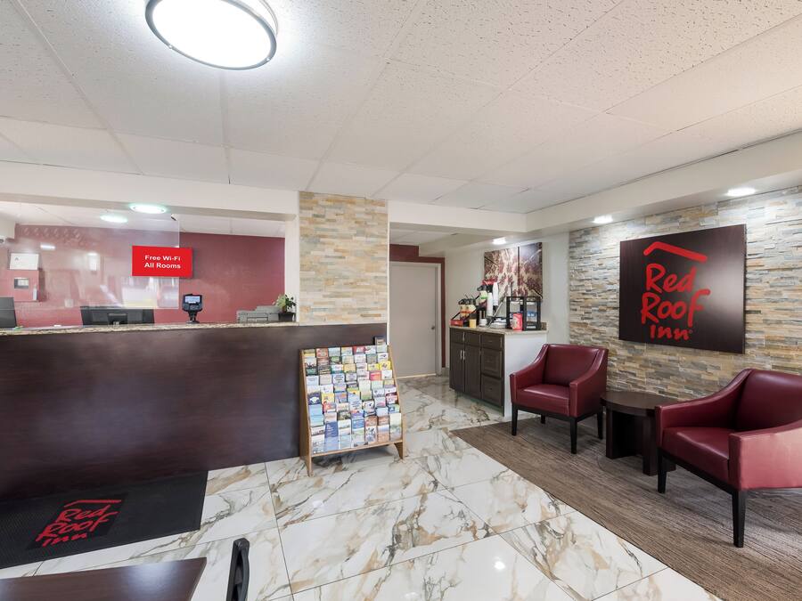 A reception area with a desk, a wall-mounted sign indicating free Wi-Fi, a magazine rack, and red seating.