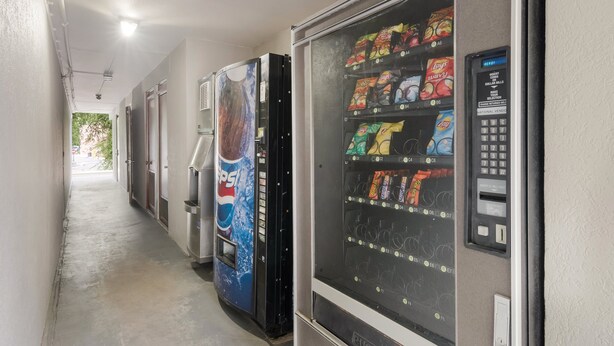 A hallway with vending machines, including a Pepsi cooler and a machine with snacks and drinks. - Red Roof Inn Lenoir (Lenoir)