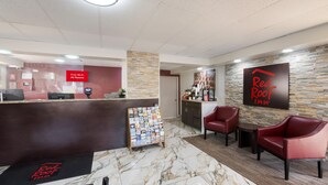 A Red Roof Inn reception area with a marble floor, a reception desk, a coffee station, and red leather chairs. - Red Roof Inn Lenoir (Lenoir)