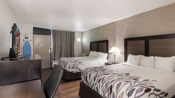 A hotel room with two beds, a desk, and a TV.