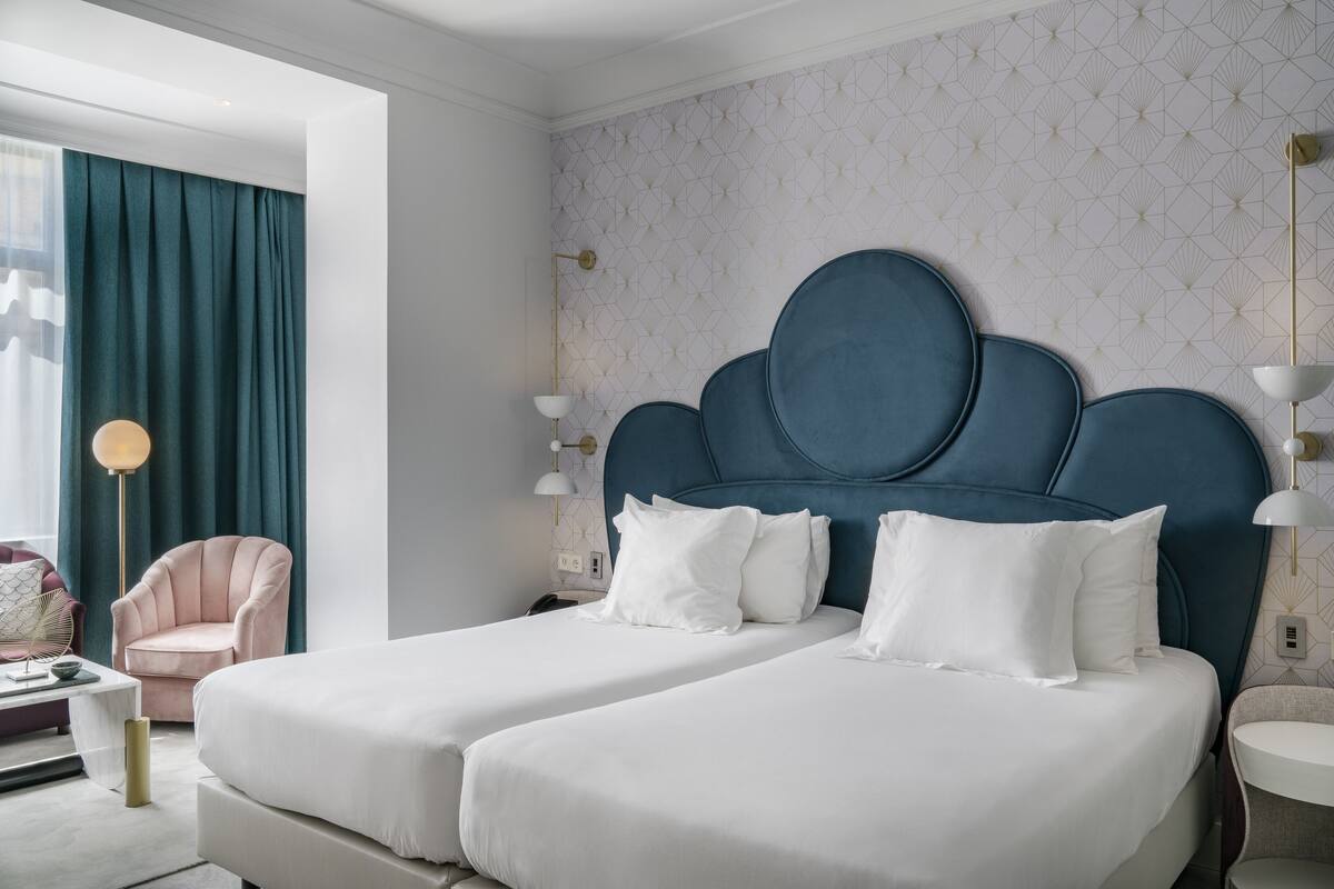 A hotel room with a large bed, two bedside tables, a chair, and a lamp.
