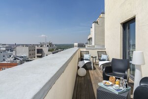 A balcony with a dining setup including a table, chairs, and a view of the cityscape.