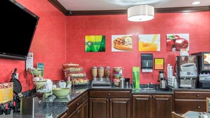 Eine Küchenzeile mit roter Wand, einem großen Bildschirm und verschiedenen Lebensmitteln, die auf der Arbeitsplatte präsentiert werden.