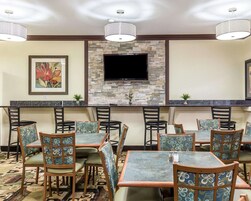 Un restaurante con pared de piedra, televisor de pantalla plana y sillas y mesas con diseños.