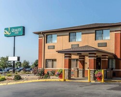 Un hotel Quality Inn con un edificio de dos plantas, un acceso cubierto y un estacionamiento con varios coches.