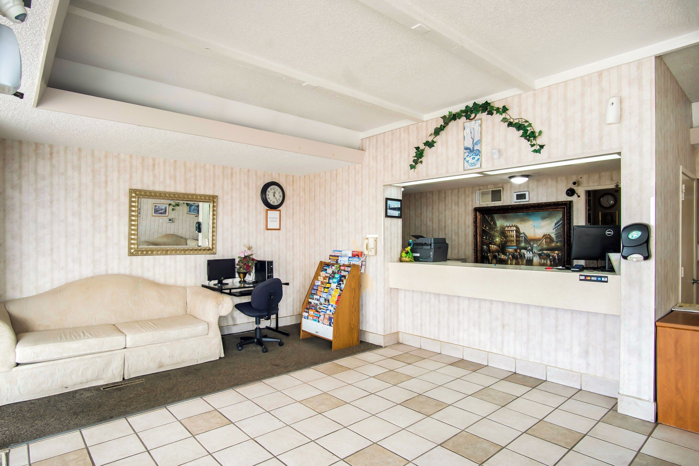 A reception area with a desk, computer, and a framed painting.