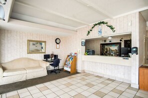 A reception area with a desk, computer, and a framed painting. - OYO Hotel Hutchinson KS West 4th Ave (Hutchinson)