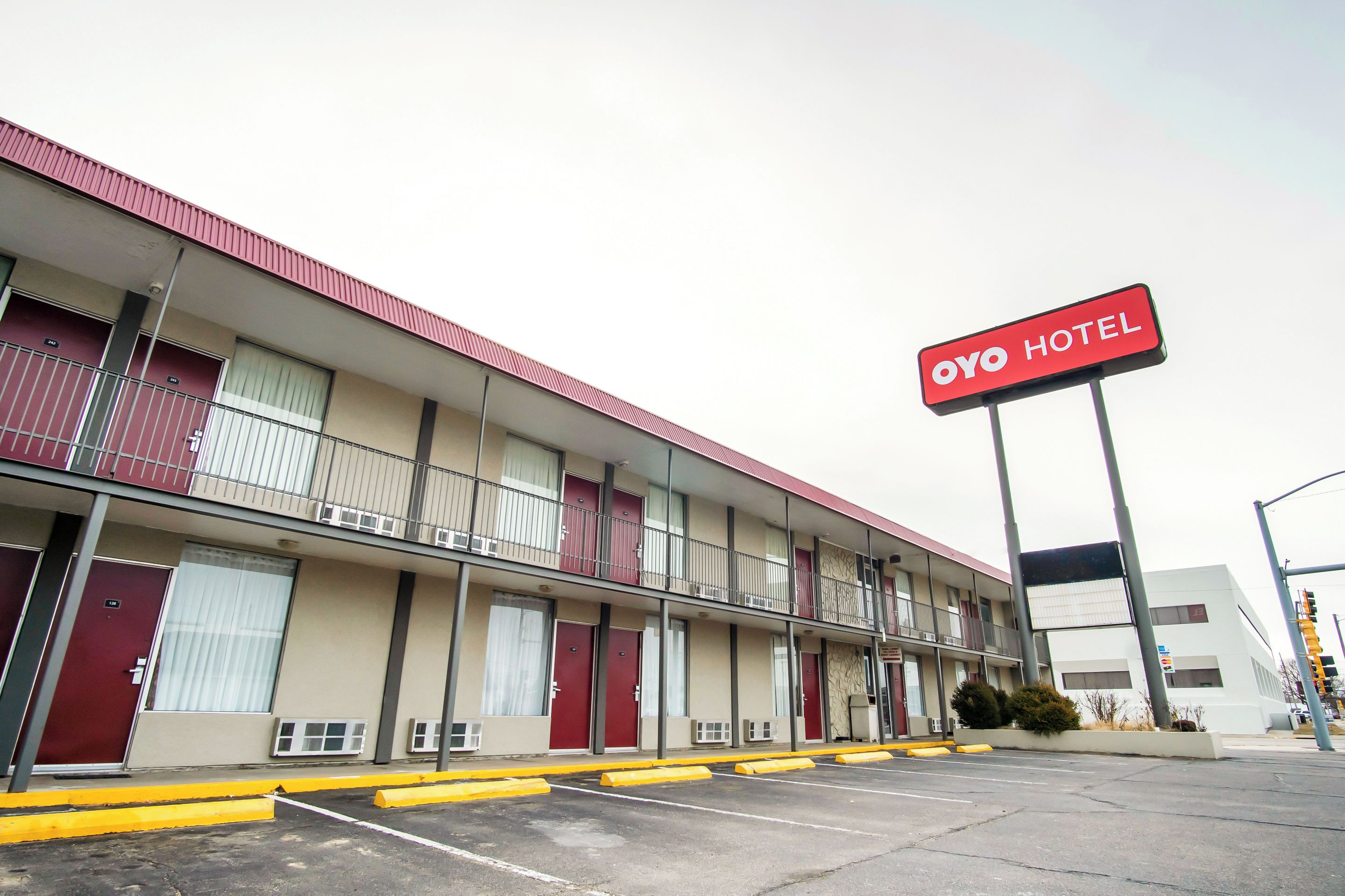A motel with a red sign indicating 'Oyo Hotel.' It features multiple floors with balconies, and a parking lot with yellow curbs.