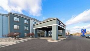 A hotel with a blue exterior, a covered entrance, and a parking lot.