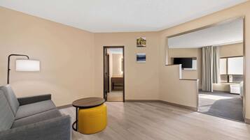 A modern hotel room with a sofa, a small round table, and a television.