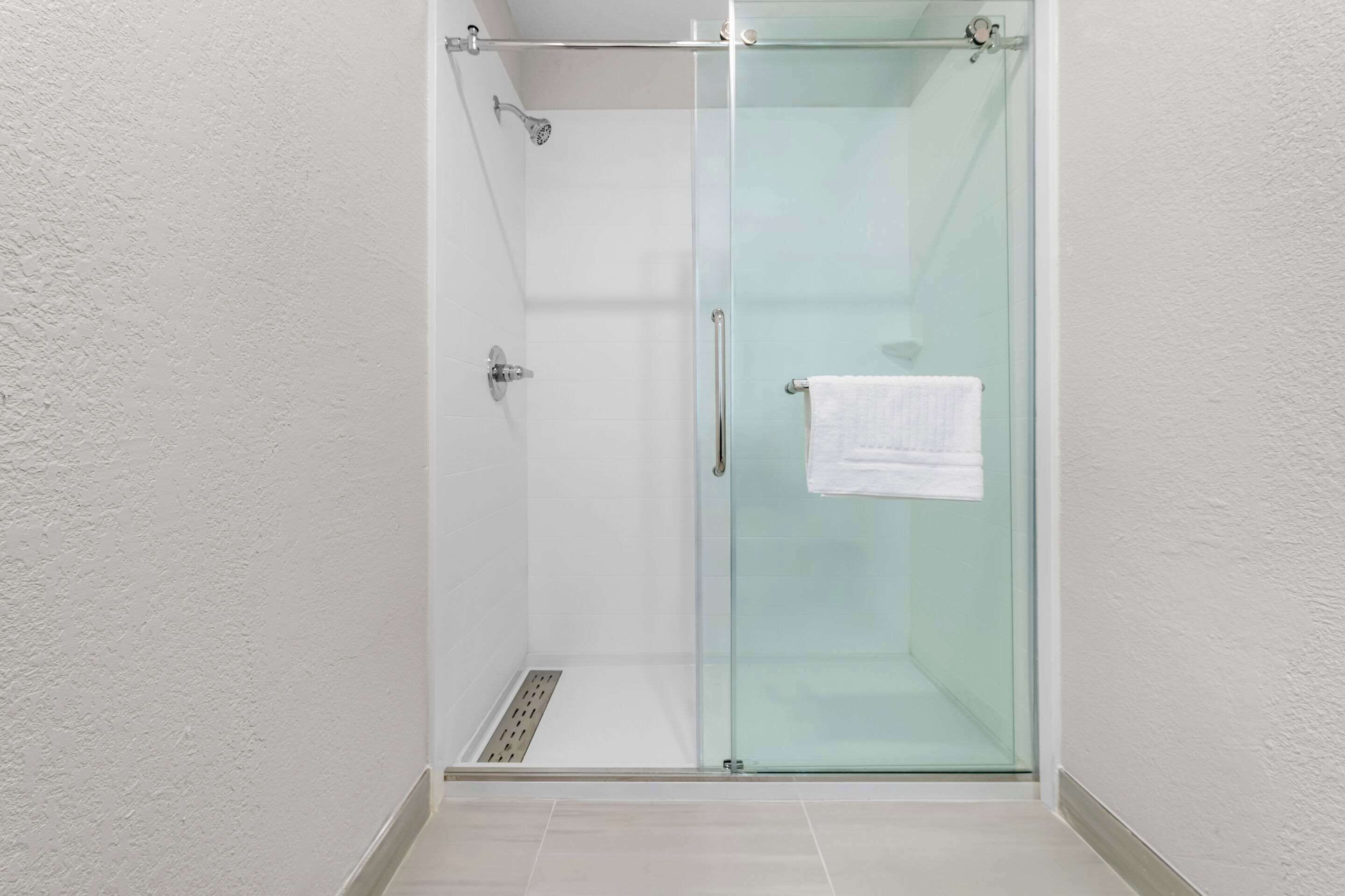 A glass-enclosed shower stall with a white towel hanging on the door handle.