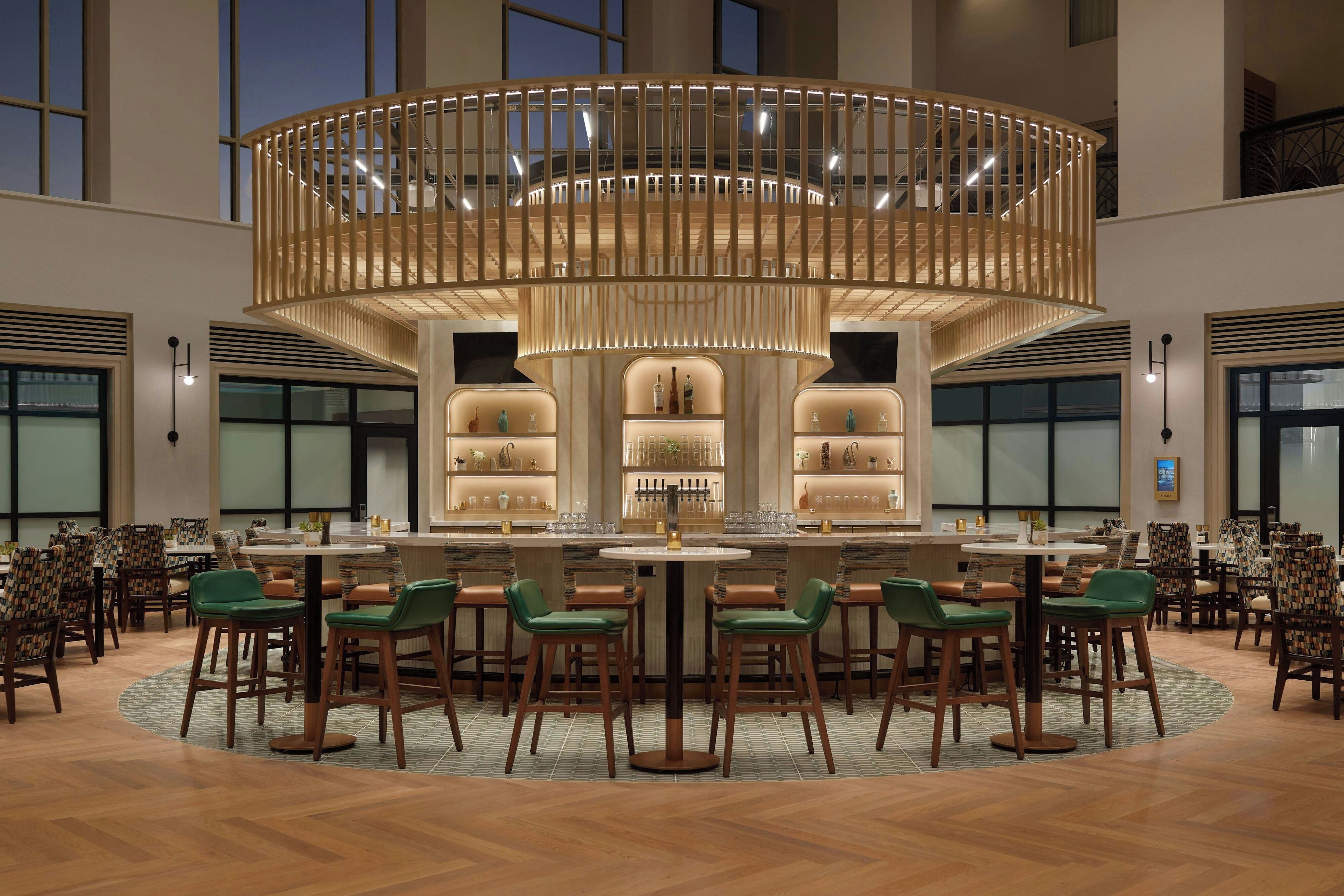 A spacious bar area with a central circular bar, multiple seating arrangements, and a modern chandelier.
