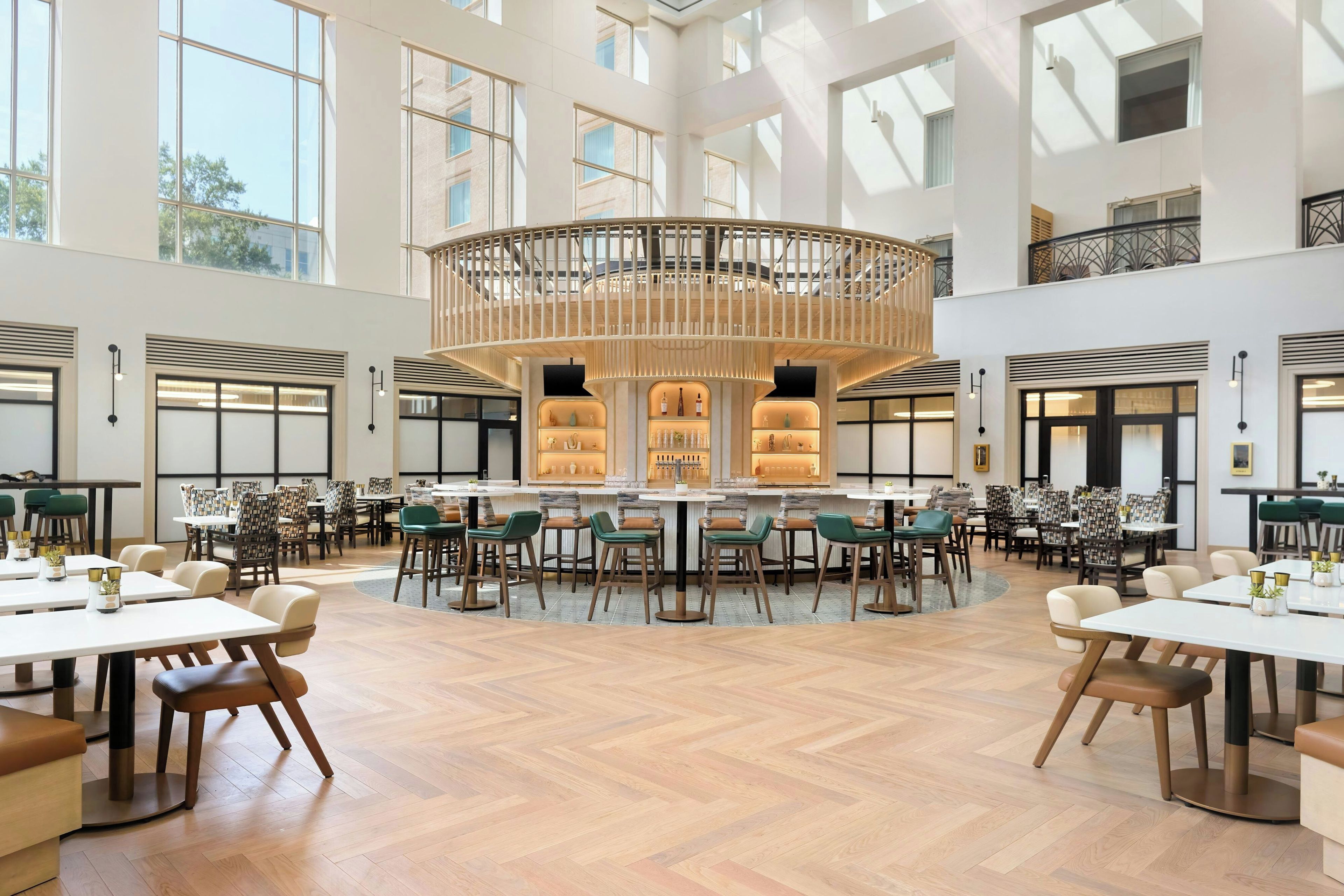 Un grand espace intérieur aménagé avec de nombreuses tables et chaises disposées autour d’un bar central.