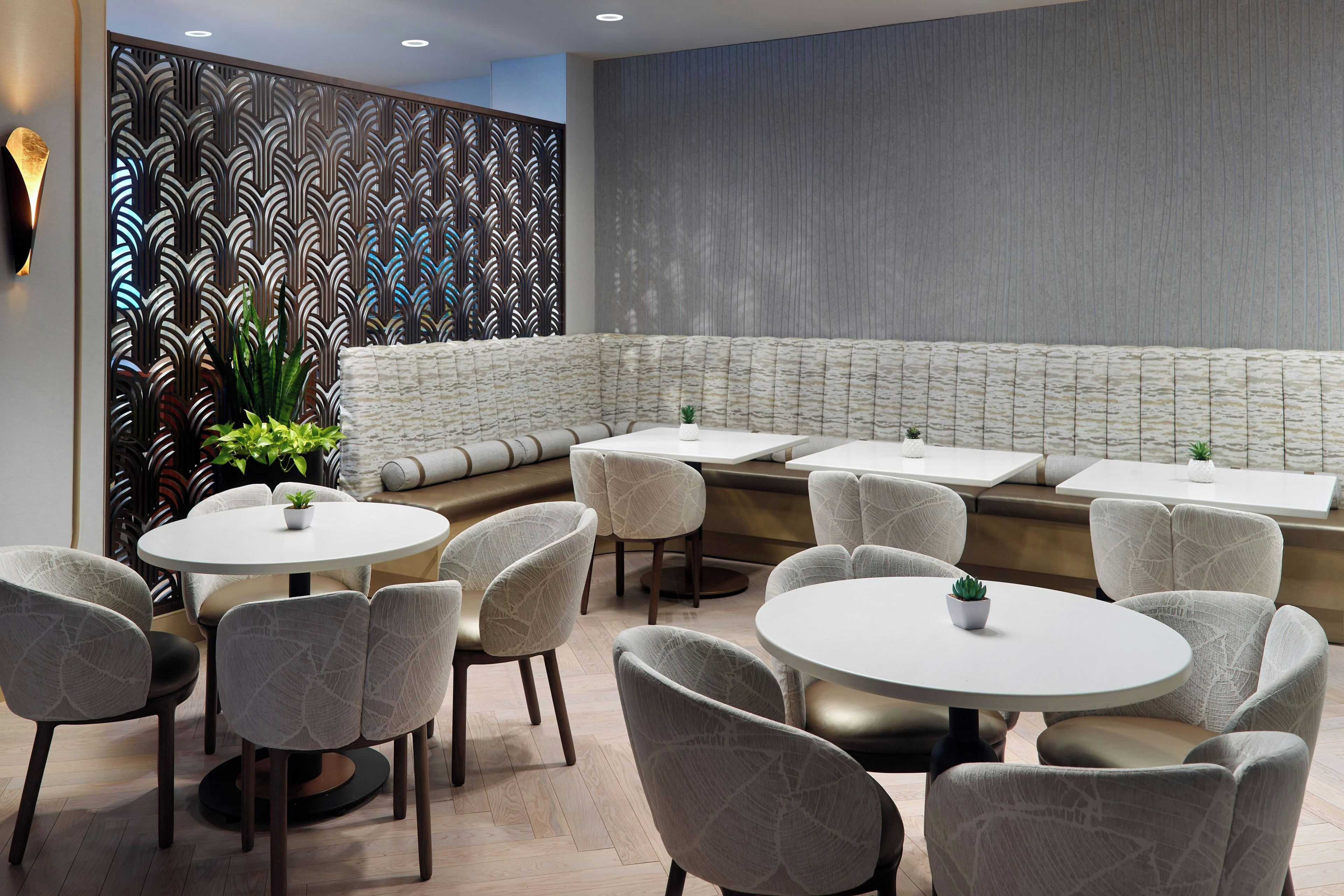 Un intérieur de restaurant moderne avec des tables rondes et des sièges rembourrés, un mur décoratif et un plancher en bois.