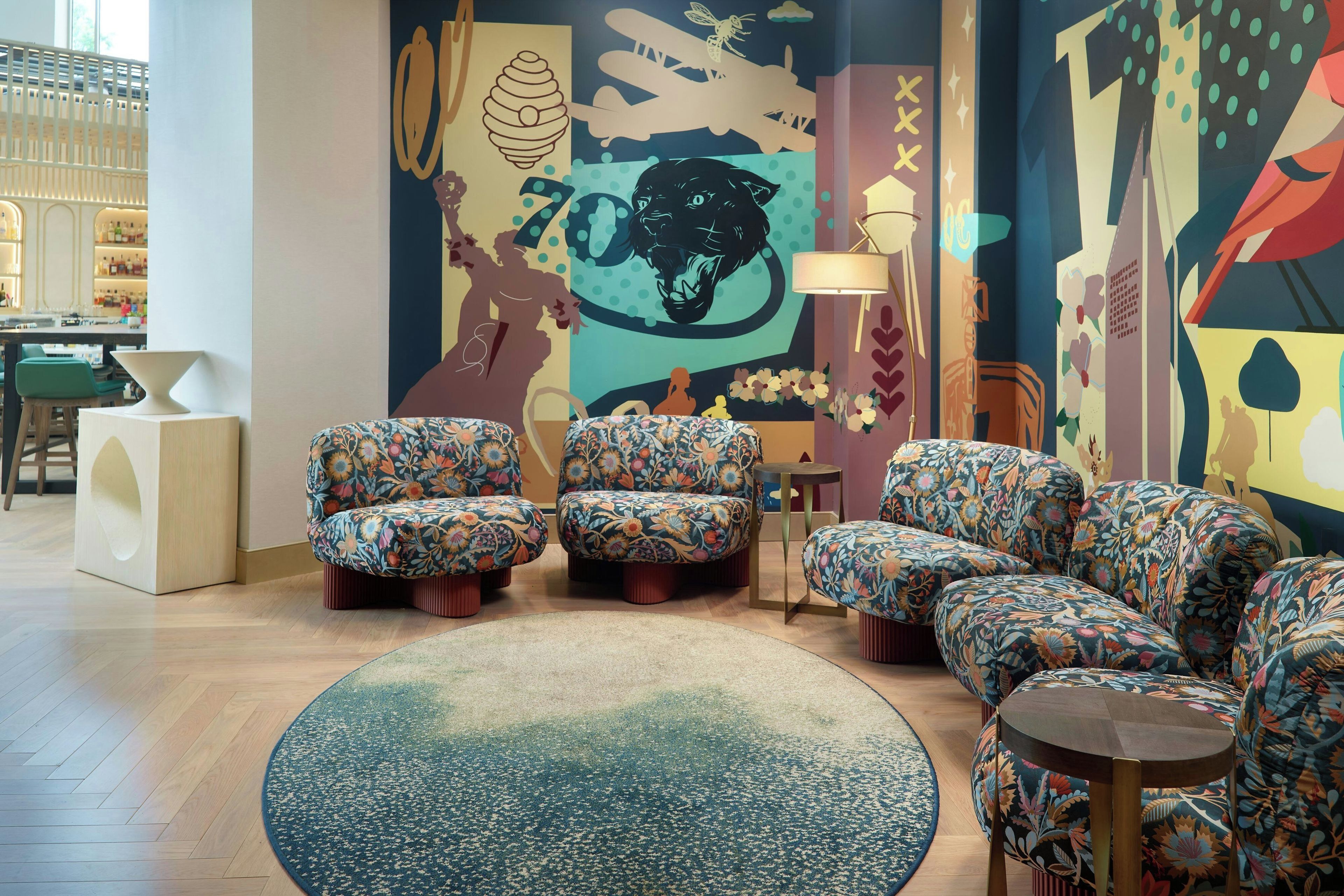 Un espace détente avec des fauteuils à motifs floraux, un tapis rond et un bar en arrière-plan.