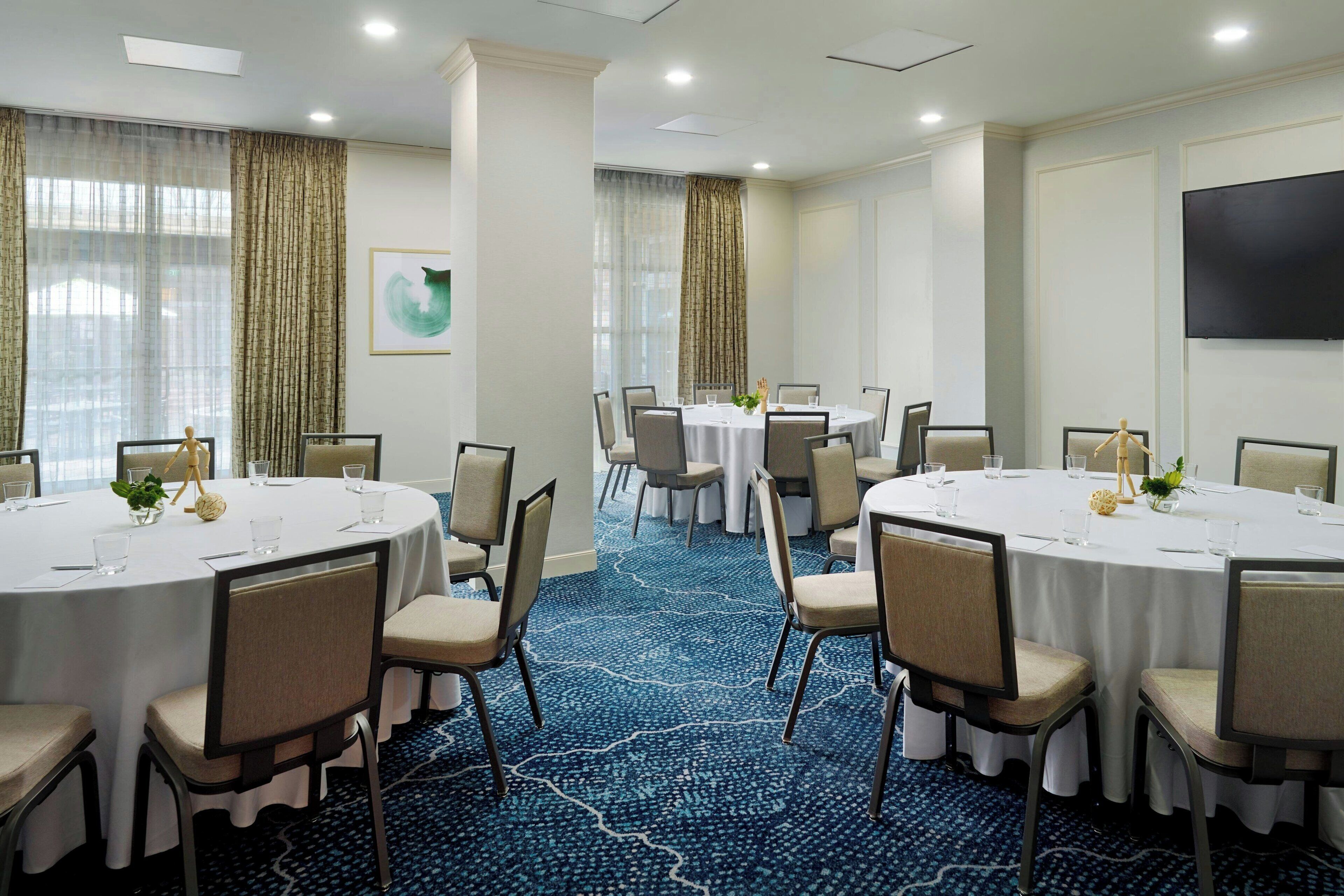 A conference room with round tables, chairs, and a blue carpet.