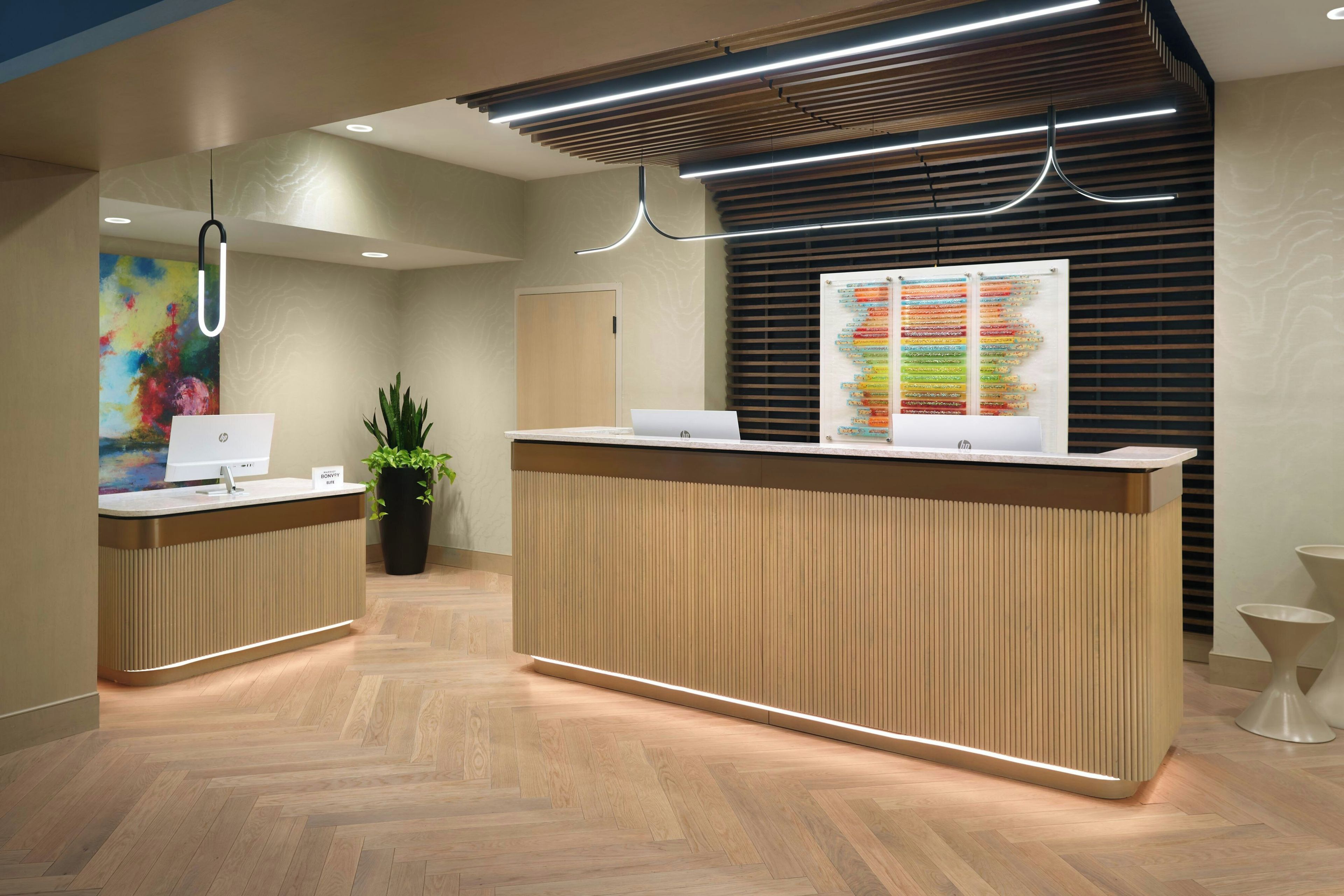 A reception desk with a computer, a potted plant, and a colorful map on the wall.