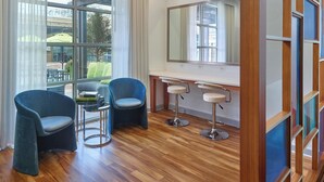 Un baño moderno con un espejo grande, piso de madera y dos taburetes.