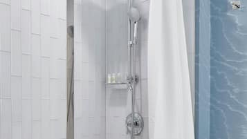 Un baño moderno con una bañera independiente, una ducha a pie con cabezal de ducha curvo y un cerramiento de vidrio.