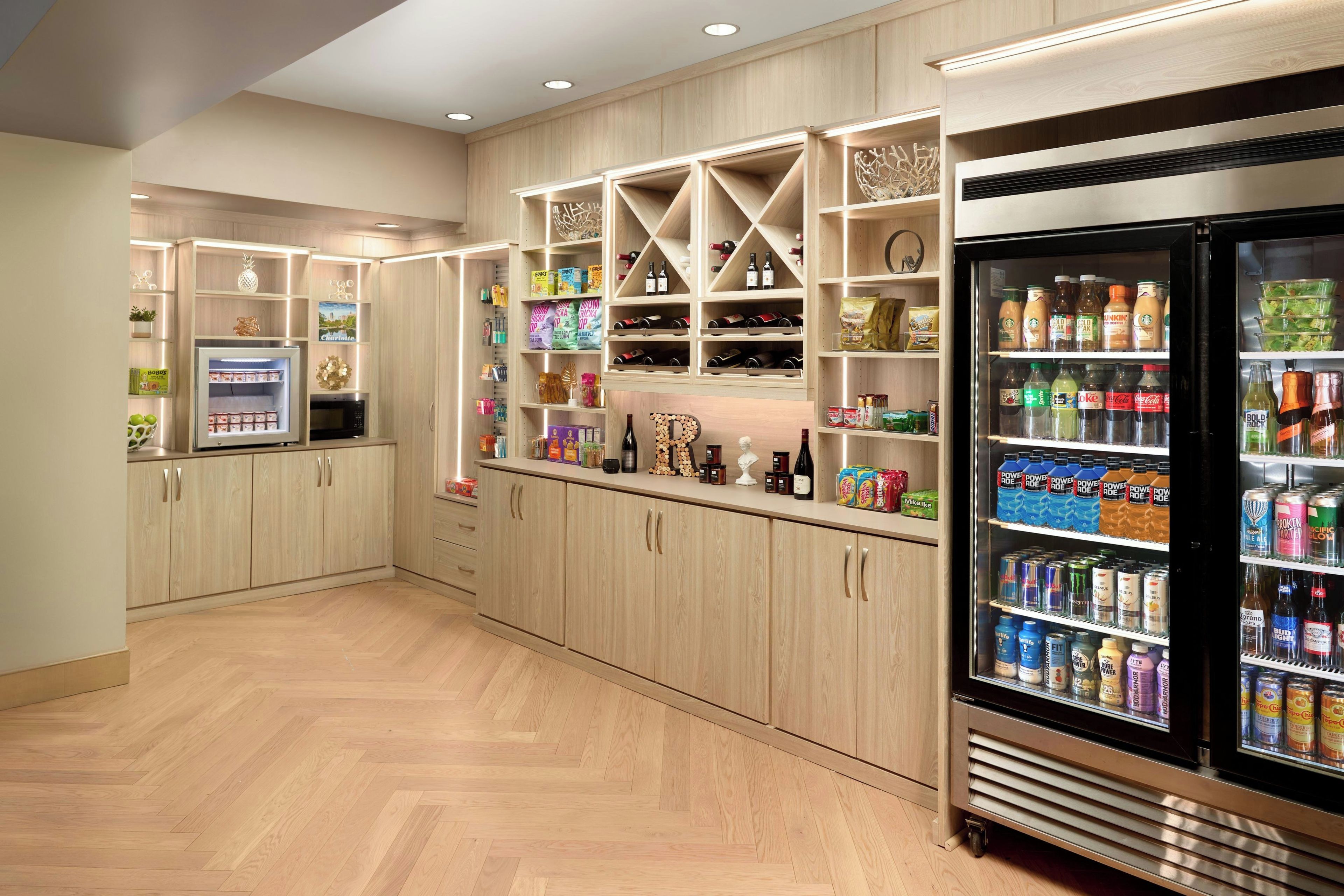 Una cocina bien organizada con armarios de madera, un refrigerador lleno de bebidas y diversos electrodomésticos.