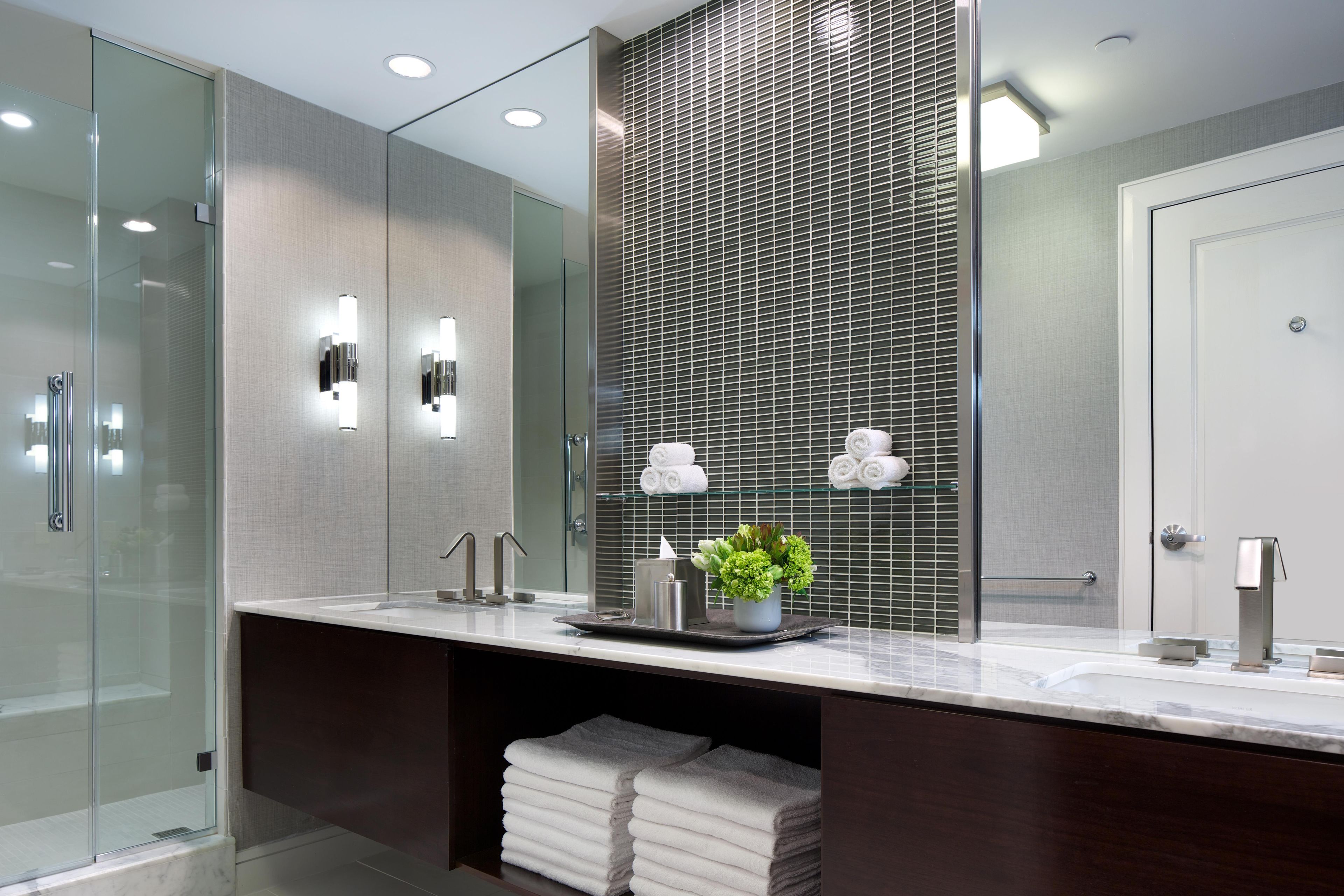 A modern bathroom with a glass shower enclosure, a vanity with a marble countertop, and a large mirror.