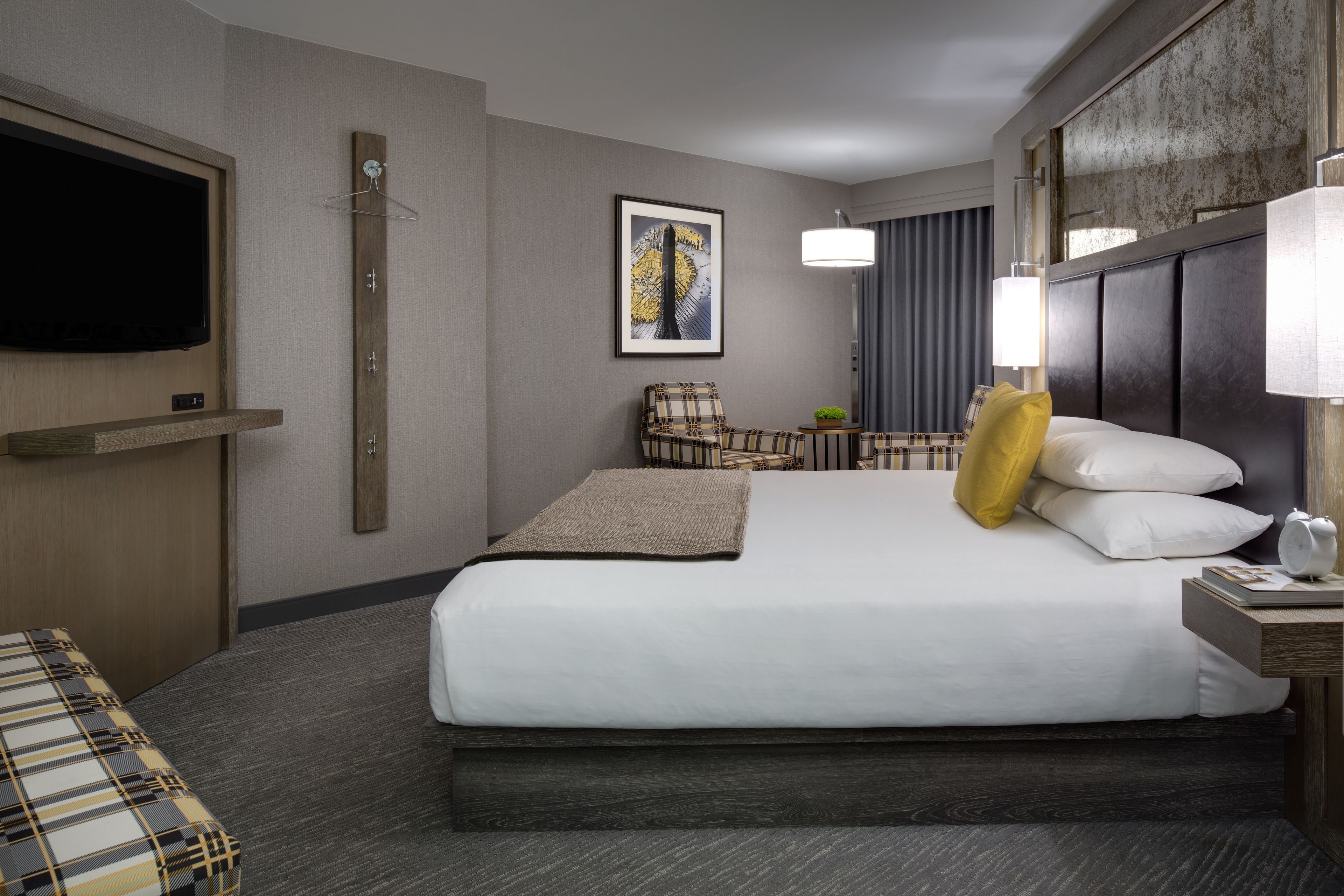Une chambre d’hôtel avec un grand lit, un téléviseur à écran plat fixé au mur, une chaise, une petite table et une lampe.