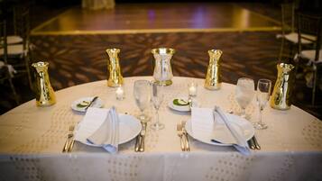 A table set for a formal event with multiple place settings, glasses, and decorative vases.