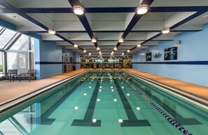 A swimming pool with lanes, a sunroof, and exercise equipment in the background.