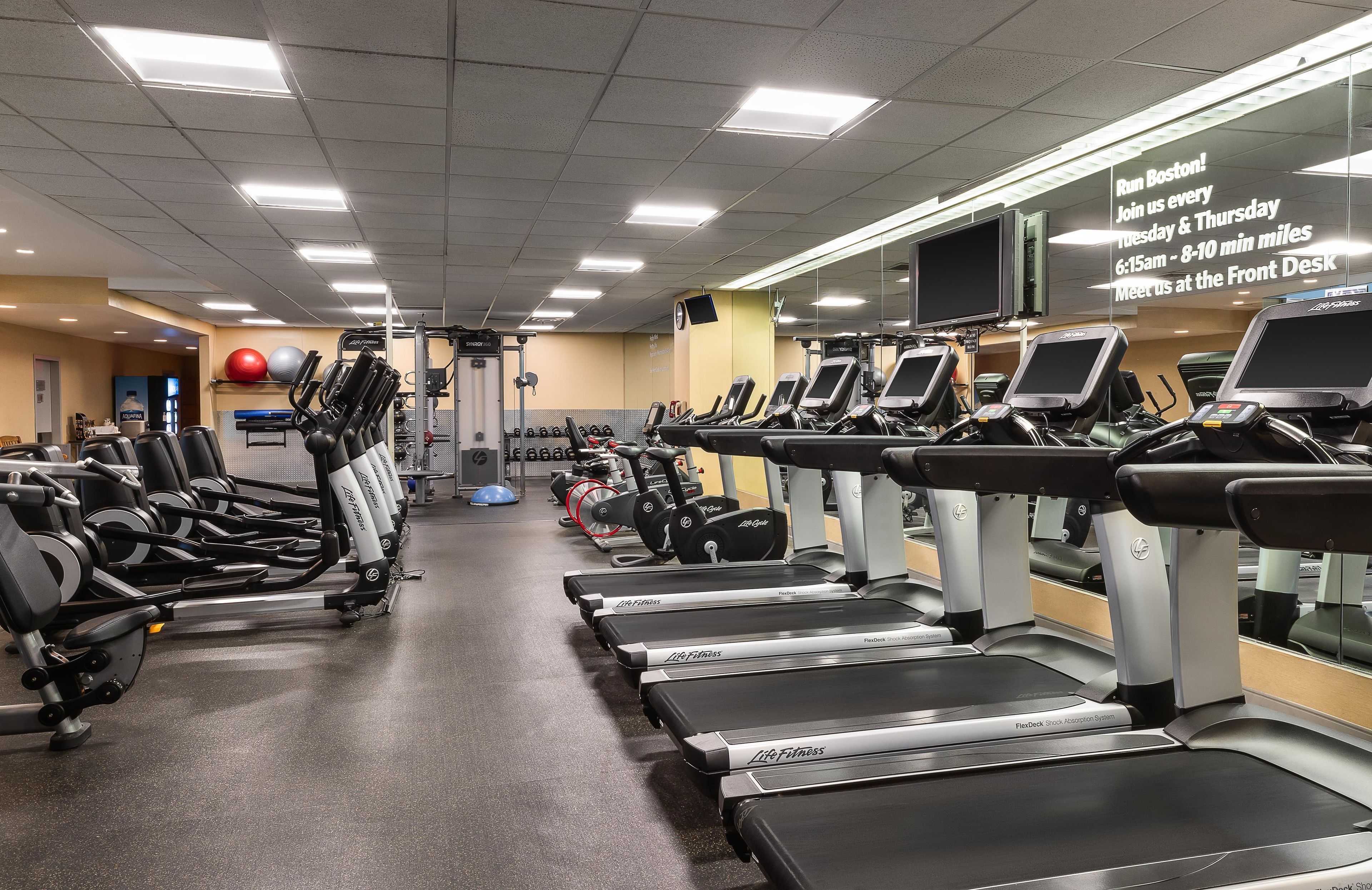 Un gimnasio con cintas de correr, máquinas de pesas y pelotas de ejercicio.