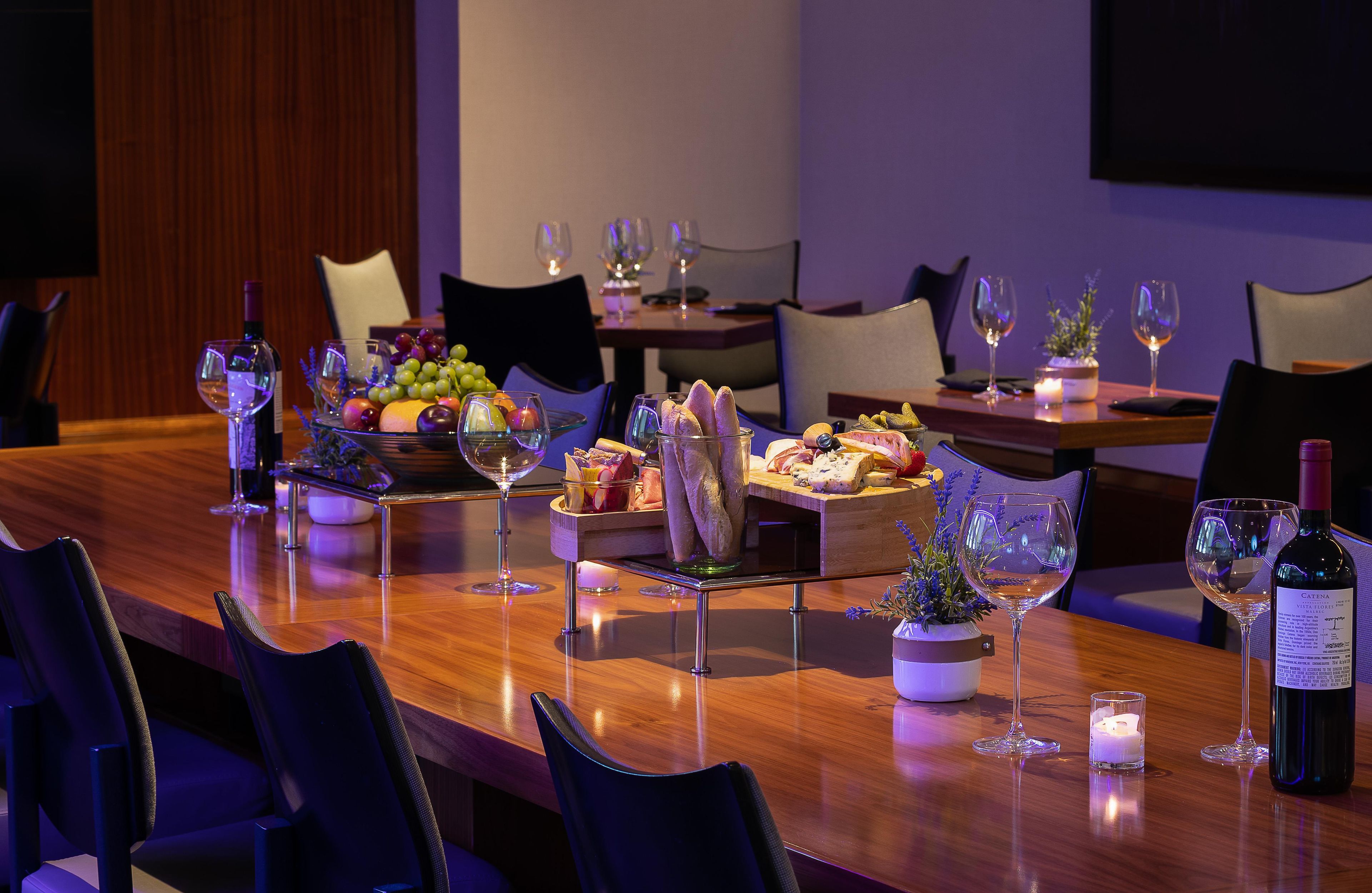 A dining table set with various food items, wine glasses, and a bottle of wine.