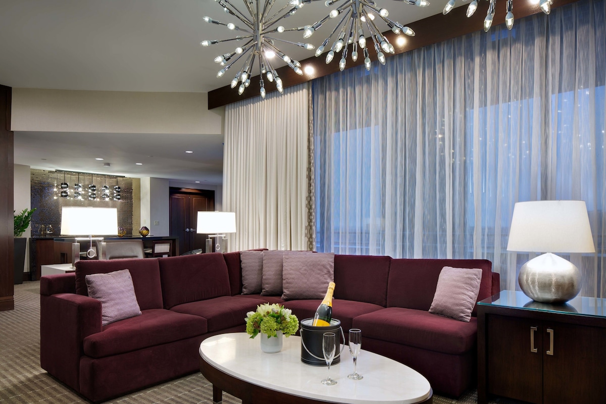 A modern living room with a sectional sofa, a round coffee table, and a chandelier.