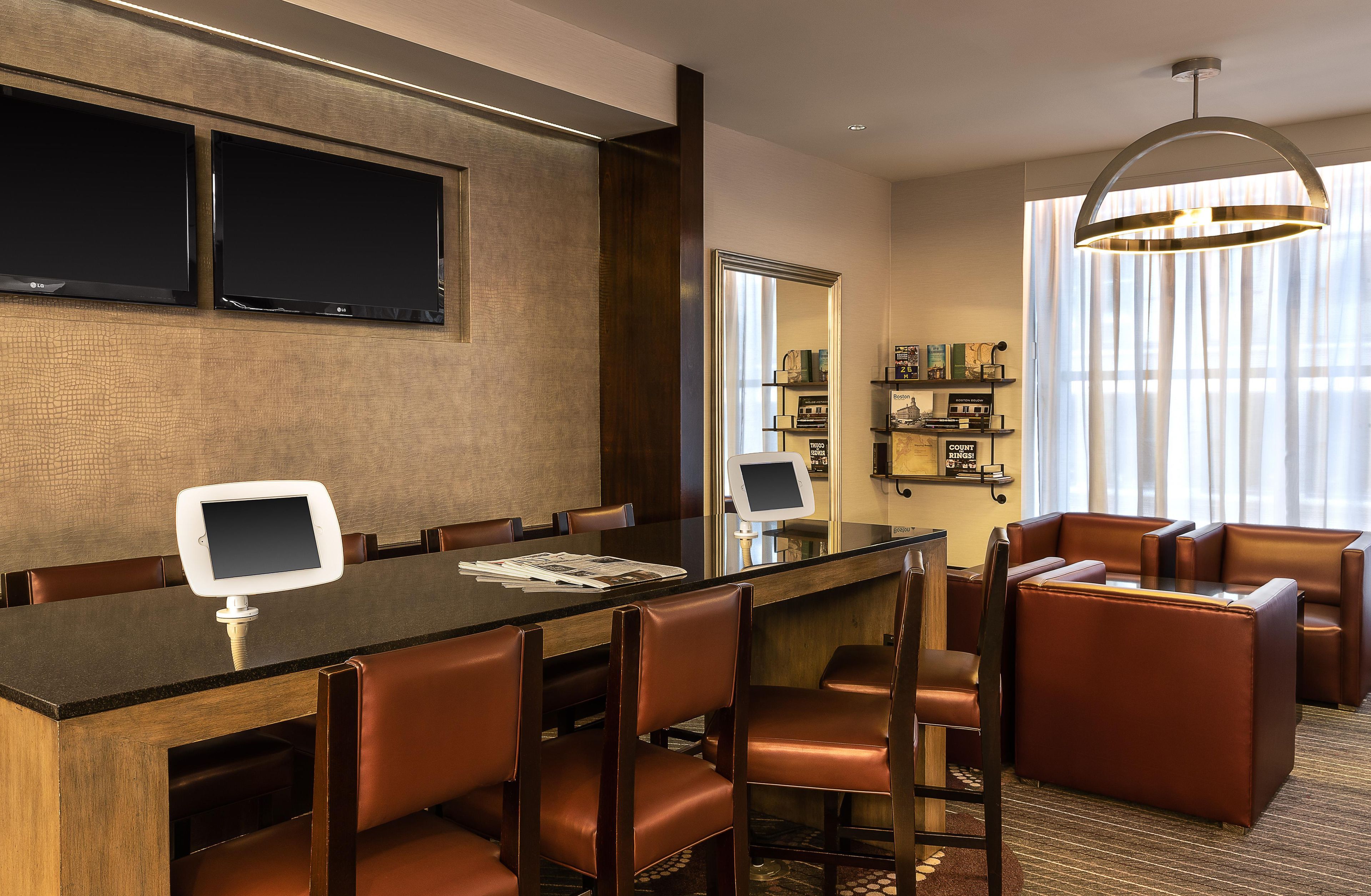 A modern hotel room with a dining area, a seating area, and a bookshelf.