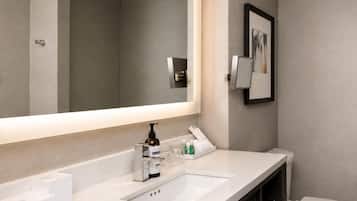 A modern bathroom with a large mirror, a white sink, and a toilet.