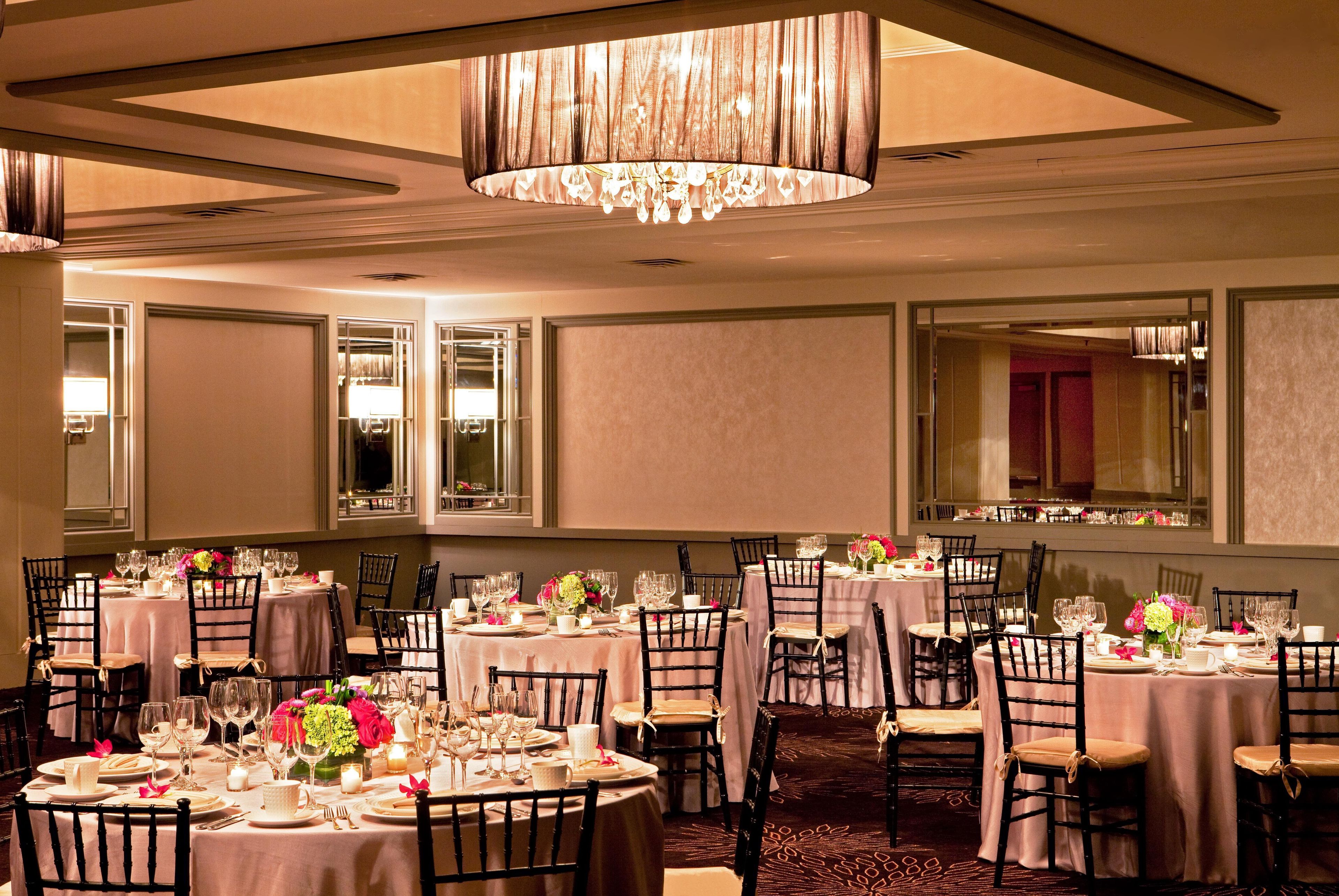 A banquet hall with round tables, chairs, and a chandelier.