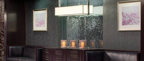 A lobby with dark wood paneling, a reception desk, two leather sofas, and framed artwork on the walls.