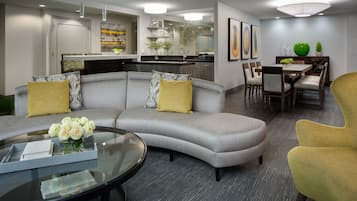 A modern living room with a gray sectional sofa, a glass coffee table, and a yellow armchair.