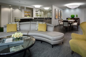 A modern living room with a gray sectional sofa, a glass coffee table, and a yellow armchair. - Hyatt Regency Boston (Boston)