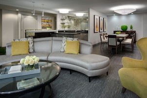 Una sala moderna con un sofá seccional gris, una mesa de centro de vidrio y un sillón amarillo.