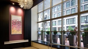 Un lobby moderno con ventanas amplias, un banco y una lámpara de techo singular.