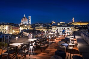 A rooftop terrace with outdoor seating, a view of historic buildings, and a clock tower in the background. - Croce Di Malta Hotel (Florence)