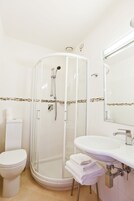 A bathroom with a glass-enclosed shower, a white toilet, and a sink with a mirror.