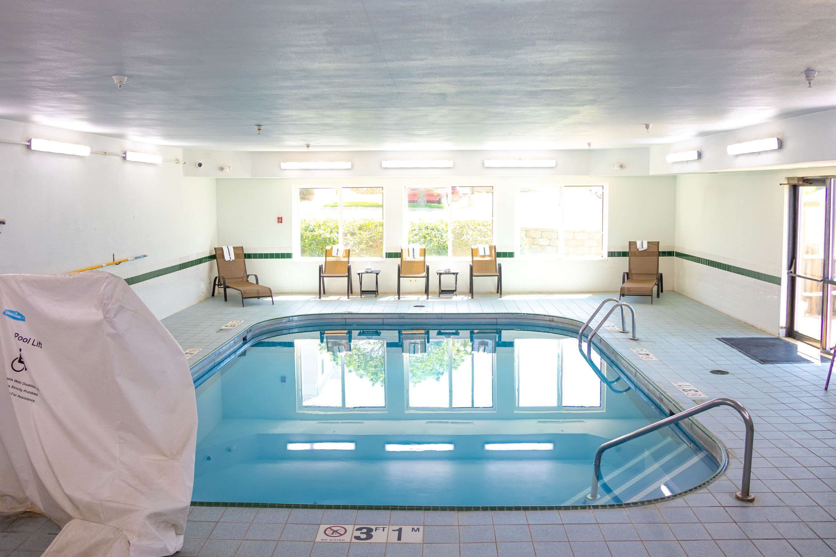 A swimming pool with a lift chair, a bench, and a chair near the pool.