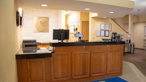 A reception desk with a wooden finish, a computer monitor, and a digital screen.