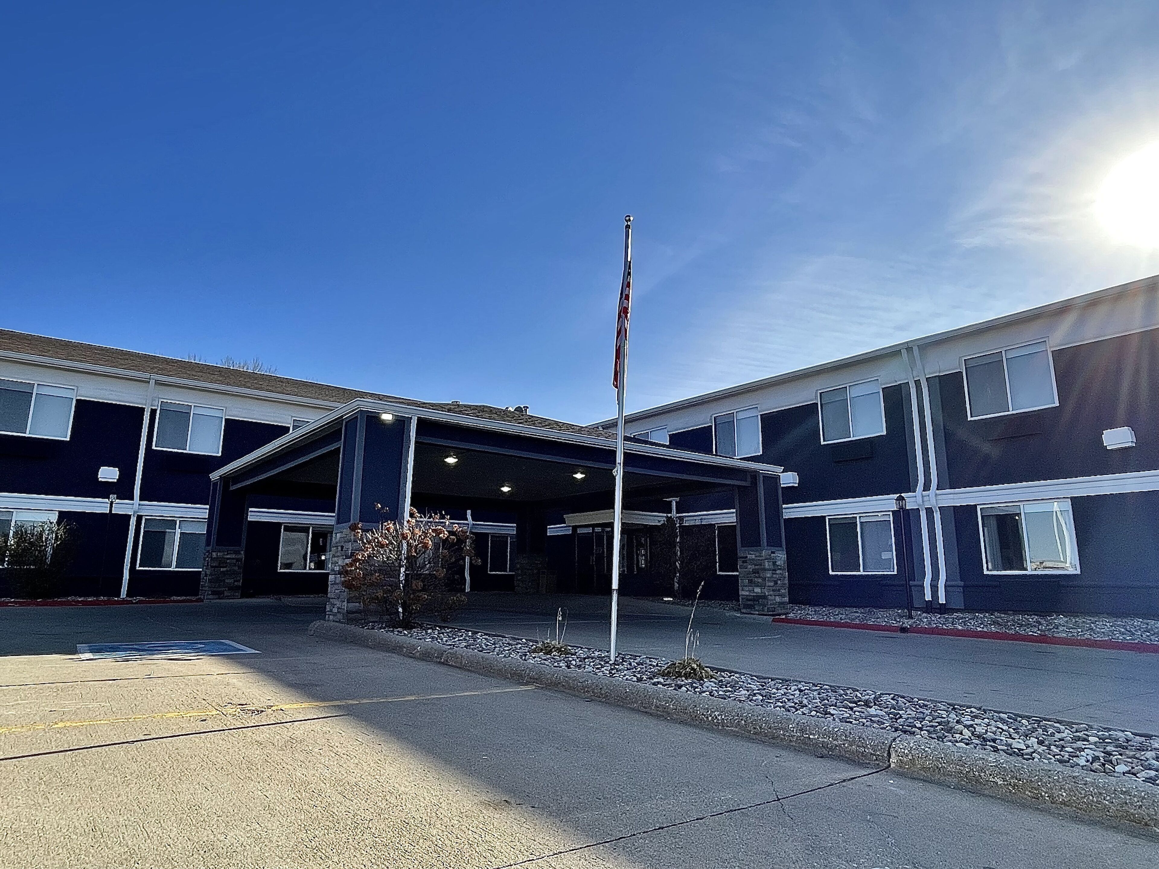 A two-story building with a covered entrance and a flagpole.