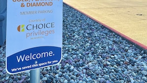 A sign for Gold, Platinum, & Diamond member parking at a building with a red roof and windows.