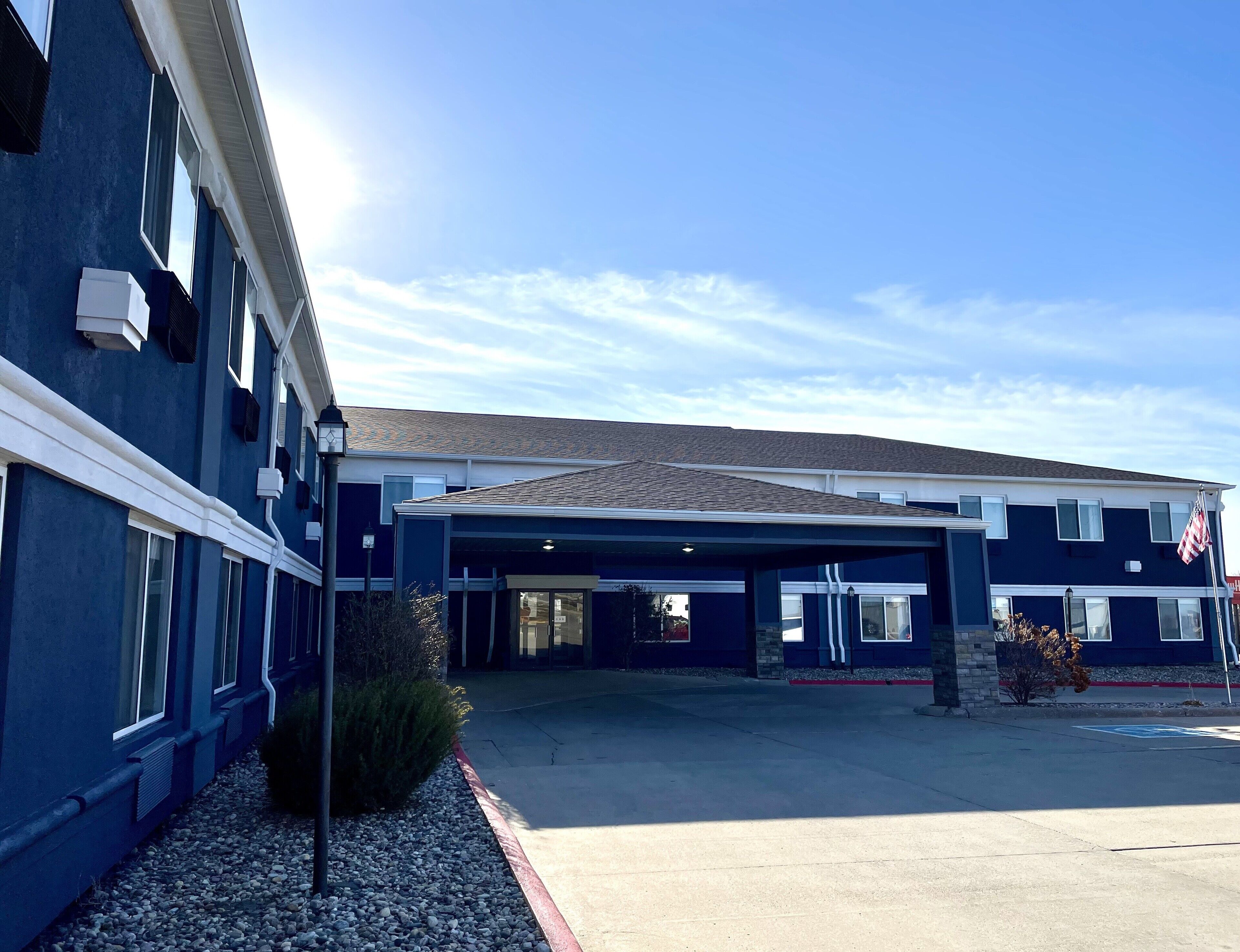 A two-story building with a covered parking area and an American flag.