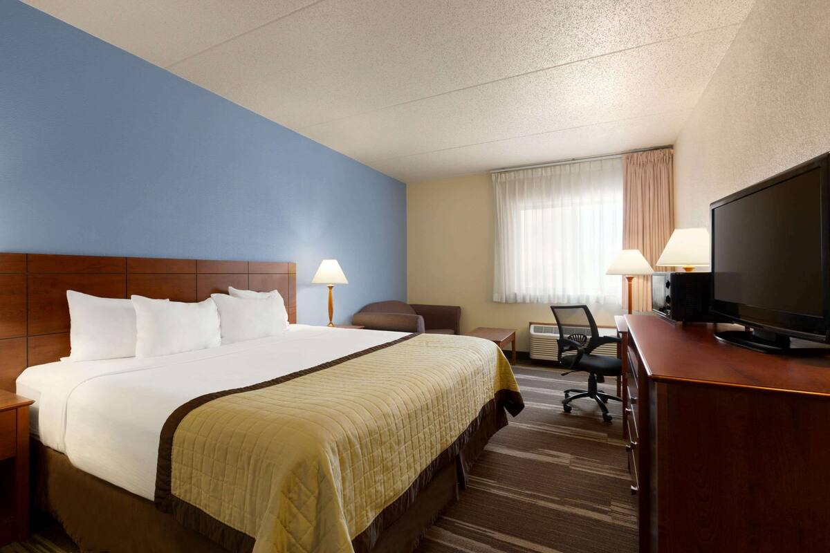 Une chambre d’hôtel avec un grand lit, deux lampes de chevet, une télévision, un bureau et une chaise.