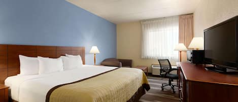 A hotel room with a large bed, two bedside lamps, a TV, a desk, and a chair.